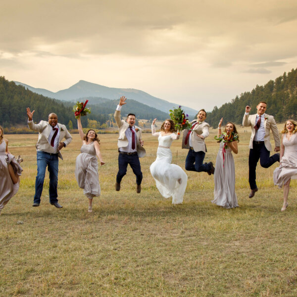 a wedding party jumping for joy at deer creek valley ranch in conifer colorado